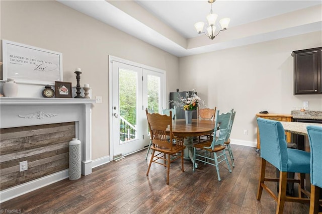 dining space with baseboards, dark wood-style flooring, a chandelier, and a fireplace