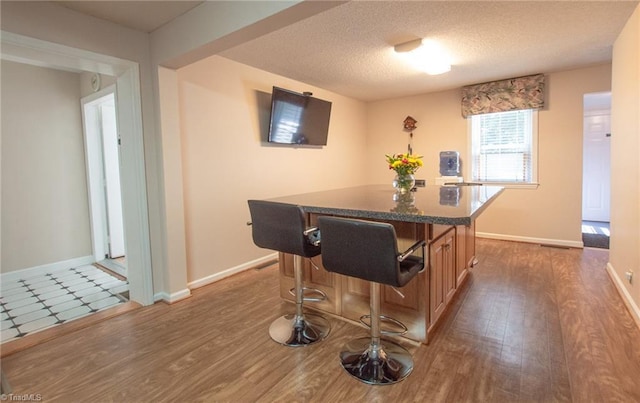 dining area with a textured ceiling, bar, and dark wood-type flooring