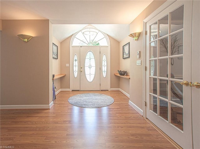 foyer featuring french doors, hardwood / wood-style floors, and lofted ceiling