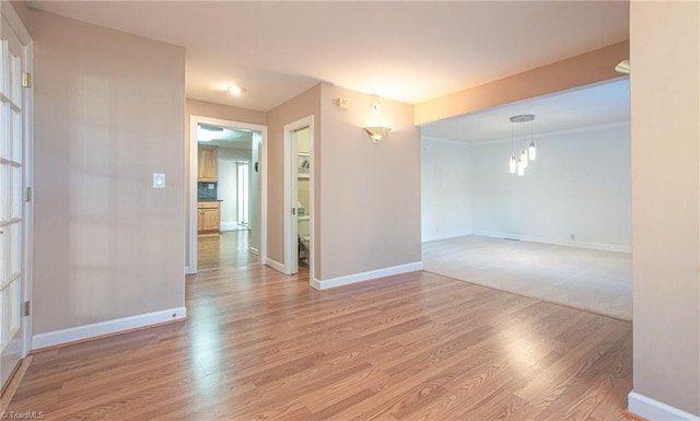 empty room with light hardwood / wood-style flooring and a notable chandelier