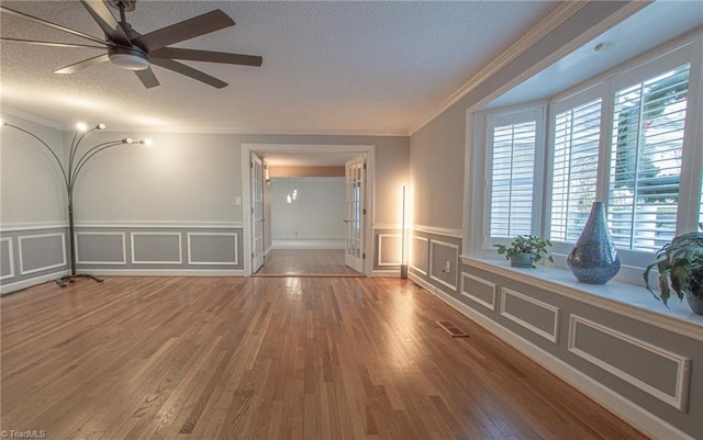 empty room with ornamental molding, hardwood / wood-style flooring, ceiling fan, and a healthy amount of sunlight