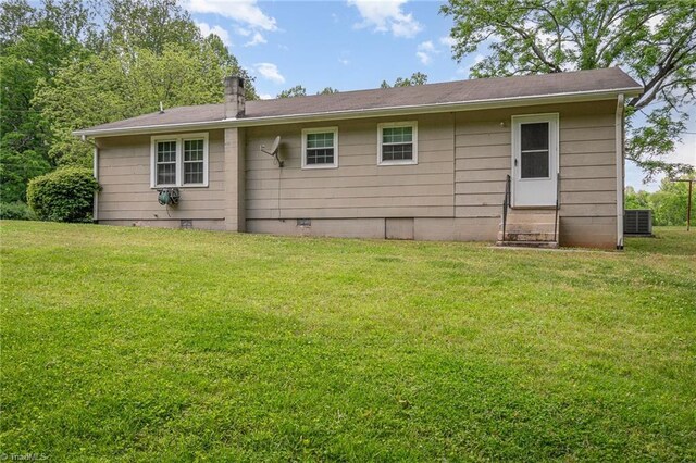 back of property with entry steps and a yard