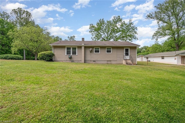rear view of house featuring entry steps and a lawn