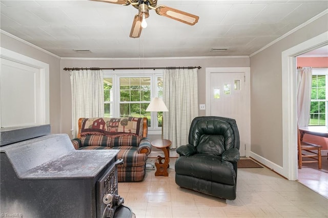 living room with ornamental molding, ceiling fan, light floors, and baseboards