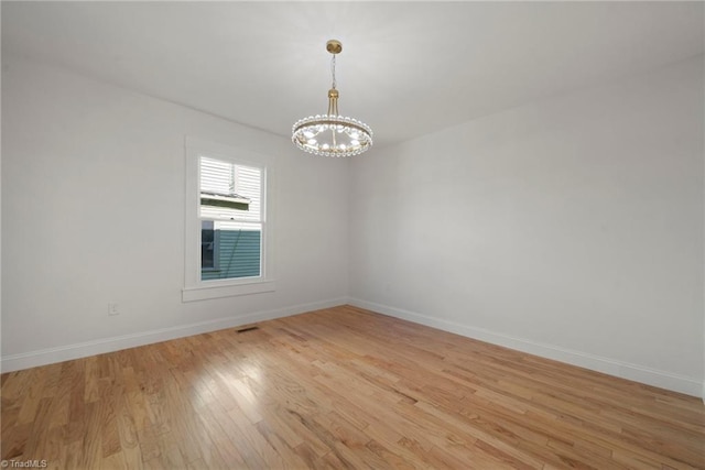 unfurnished room with a notable chandelier and light hardwood / wood-style floors