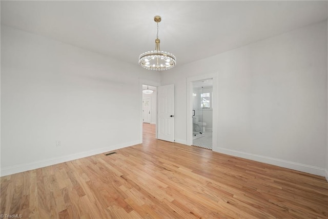 empty room with light wood-type flooring and an inviting chandelier