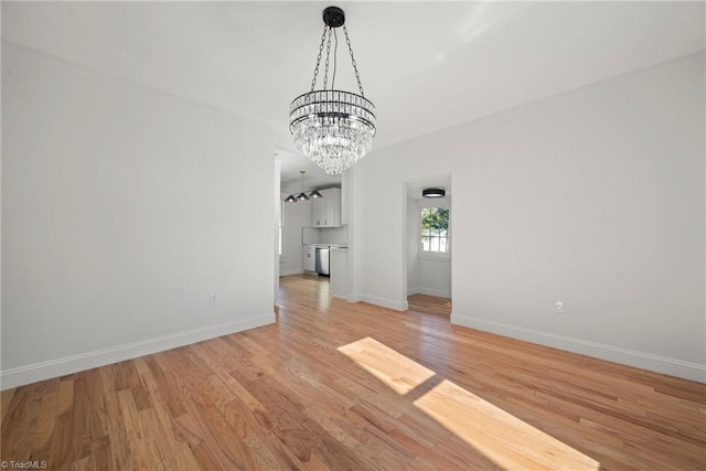 unfurnished living room featuring a notable chandelier and light wood-type flooring