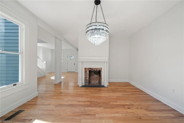 unfurnished living room featuring a notable chandelier and light hardwood / wood-style flooring