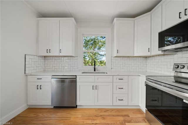 kitchen featuring stainless steel appliances, light hardwood / wood-style floors, sink, and white cabinetry