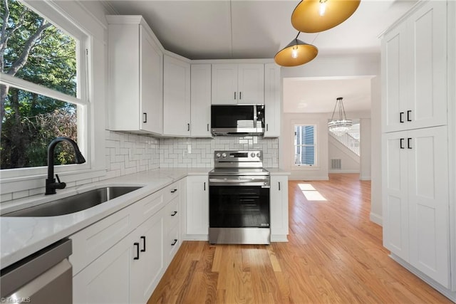 kitchen featuring light wood-type flooring, tasteful backsplash, sink, appliances with stainless steel finishes, and white cabinetry