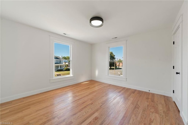 empty room with plenty of natural light and light hardwood / wood-style floors