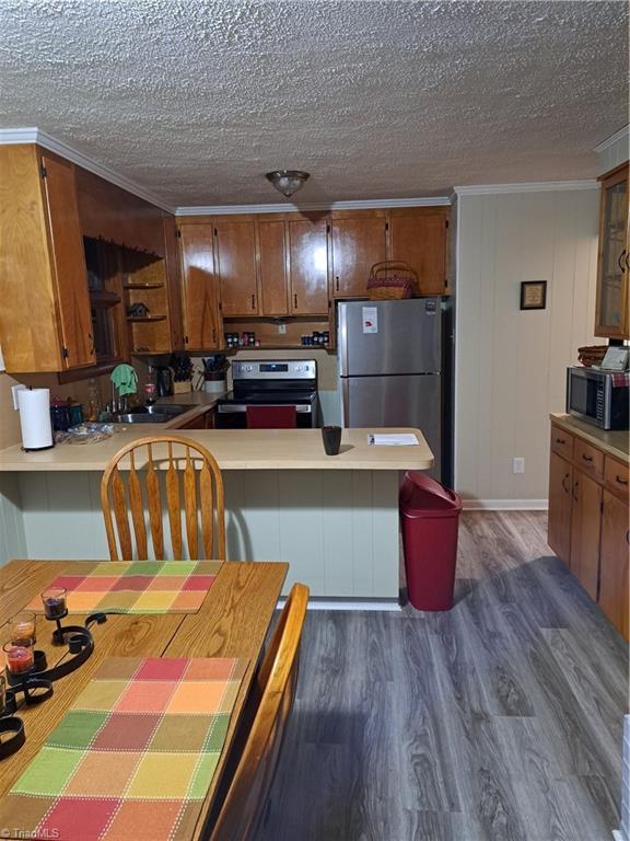 kitchen featuring sink, dark hardwood / wood-style floors, kitchen peninsula, a textured ceiling, and appliances with stainless steel finishes