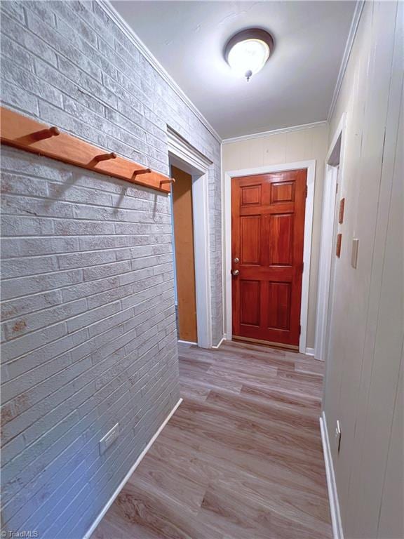 hall with ornamental molding, brick wall, and light hardwood / wood-style flooring