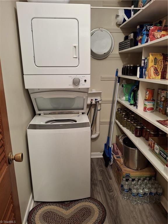 clothes washing area with stacked washer / dryer and dark wood-type flooring