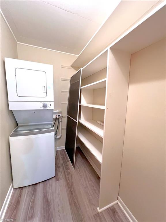 laundry area featuring light wood-type flooring and stacked washing maching and dryer