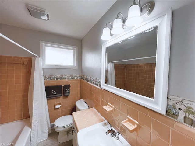 full bathroom with tile patterned floors, shower / bath combination with curtain, sink, toilet, and tile walls