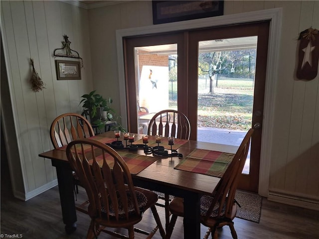 dining room with hardwood / wood-style floors, crown molding, and wood walls