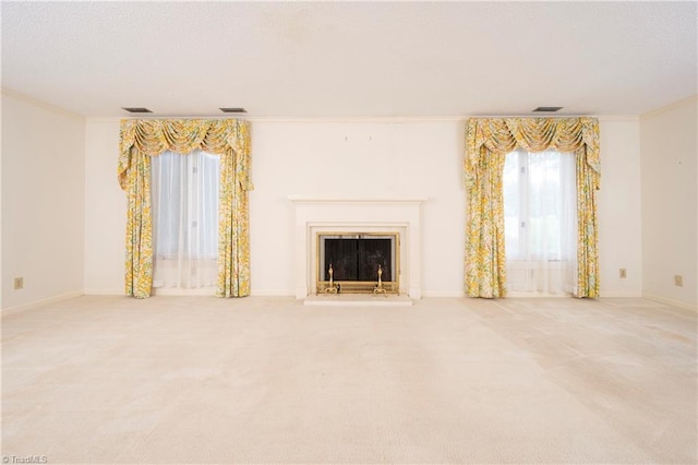 unfurnished living room with carpet floors, a fireplace with raised hearth, baseboards, visible vents, and ornamental molding