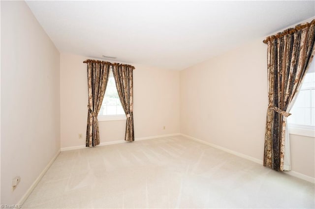 empty room featuring baseboards and light colored carpet