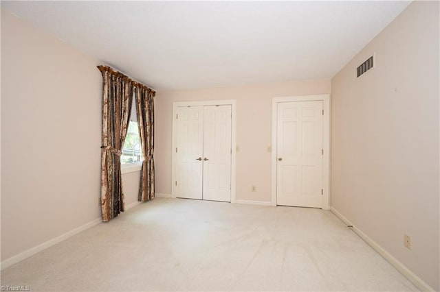 unfurnished bedroom featuring baseboards, light colored carpet, and visible vents