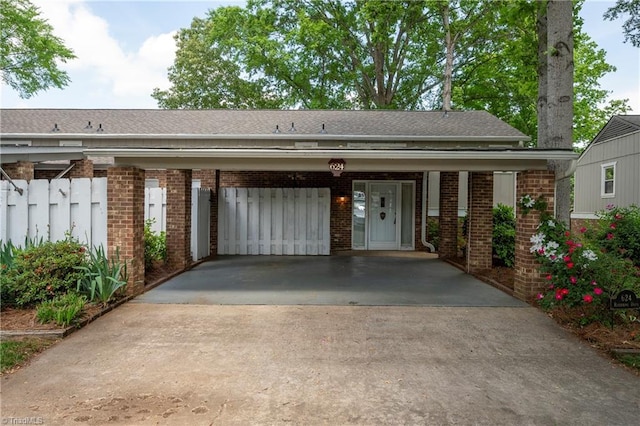 view of front of property featuring brick siding, fence, driveway, and roof with shingles