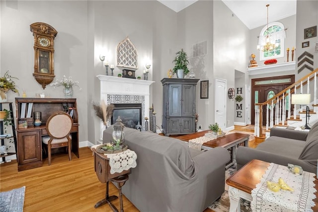 7672 Crossing Ridge Dr, Belews Creek, NC 27009 - living area featuring high vaulted ceiling, a tiled fireplace, light wood-style floors, a chandelier, and stairs