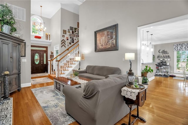 7672 Crossing Ridge Dr, Belews Creek, NC 27009 - living area with light wood-type flooring, a chandelier, a high ceiling, and stairs