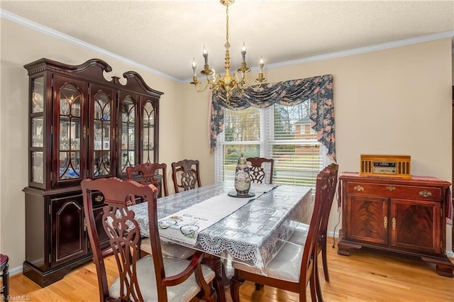 dining room with a notable chandelier, light wood-type flooring, and crown molding