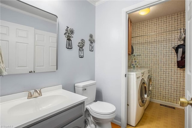 bathroom with independent washer and dryer, vanity, toilet, and crown molding