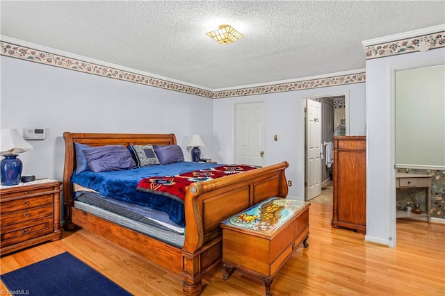 bedroom with light wood-type flooring, a textured ceiling, and ornamental molding