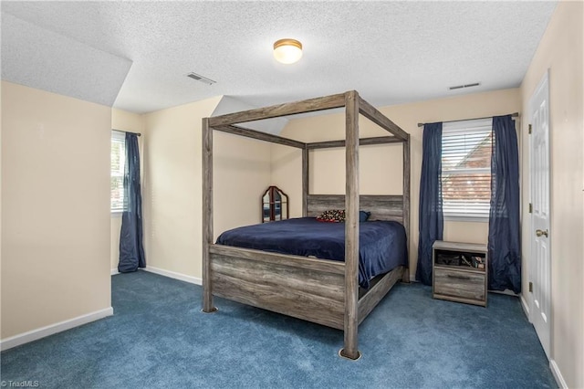 bedroom with dark carpet and a textured ceiling