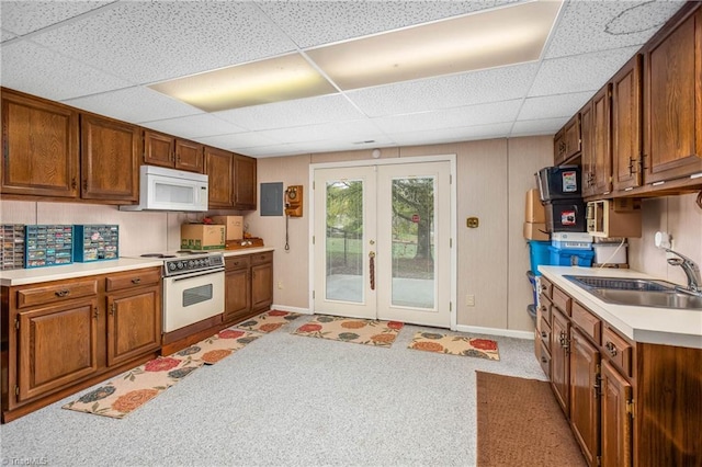 kitchen featuring french doors, sink, a drop ceiling, white appliances, and light carpet