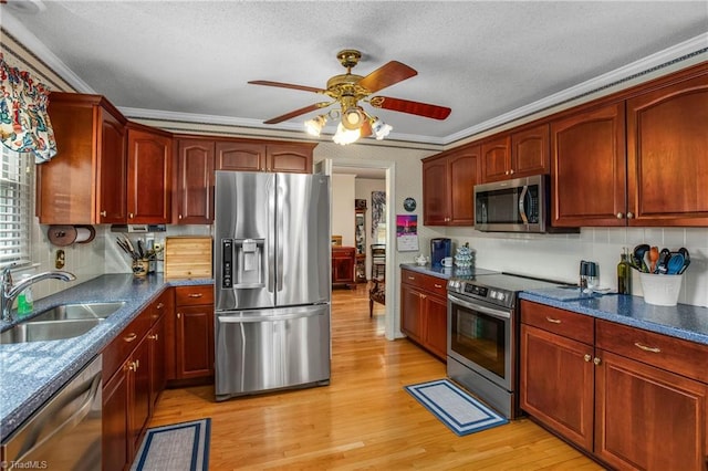 kitchen with light wood-type flooring, stainless steel appliances, ceiling fan, crown molding, and sink