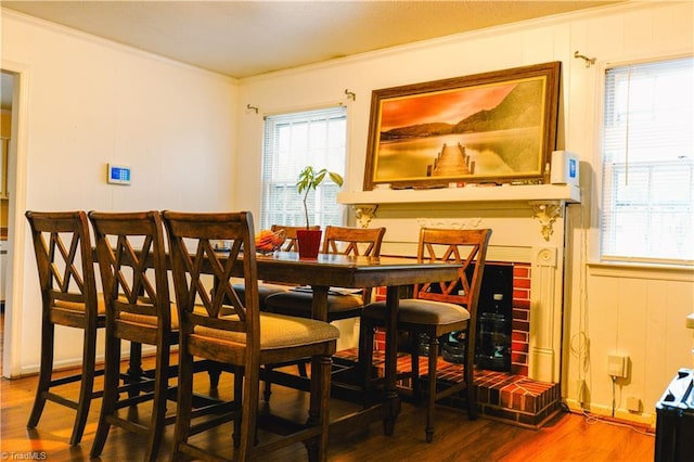 dining space featuring crown molding, plenty of natural light, wood-type flooring, and wooden walls