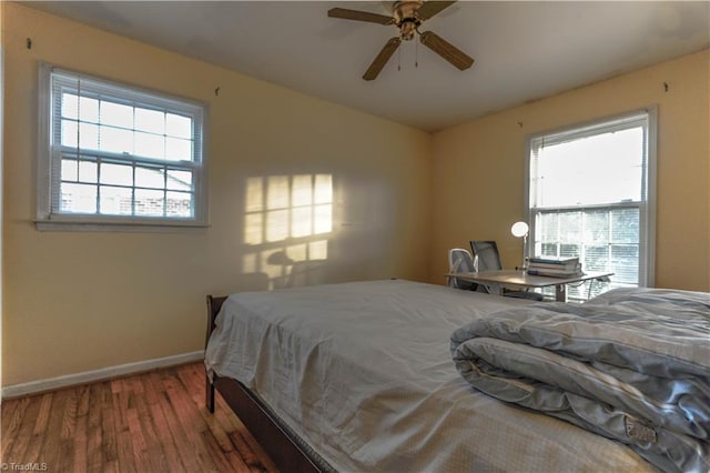 bedroom with wood-type flooring, multiple windows, and ceiling fan