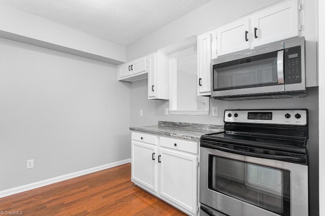 kitchen with white cabinetry, appliances with stainless steel finishes, dark hardwood / wood-style flooring, a textured ceiling, and light stone counters