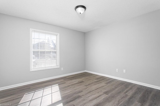 empty room with a textured ceiling and dark hardwood / wood-style floors