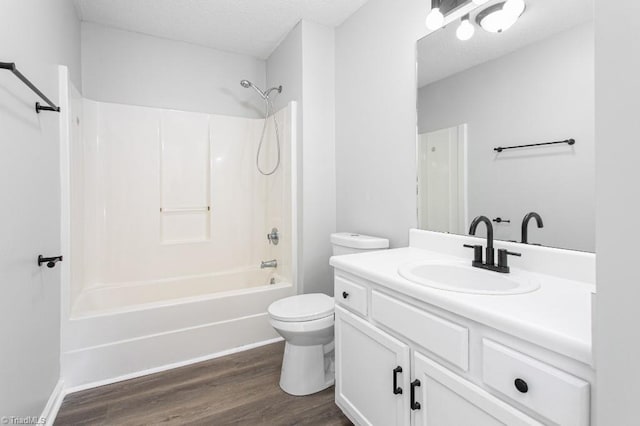 full bathroom featuring toilet, bathtub / shower combination, wood-type flooring, a textured ceiling, and vanity