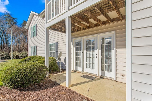 view of exterior entry with a patio area, a balcony, and french doors