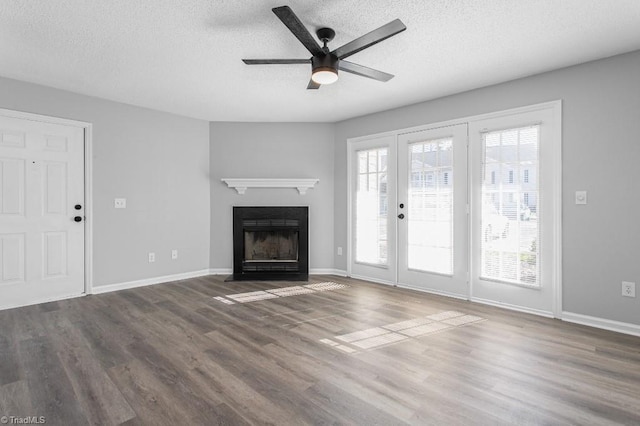 unfurnished living room featuring ceiling fan, dark wood-type flooring, and a textured ceiling