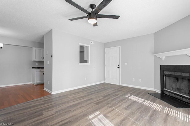 unfurnished living room with ceiling fan and wood-type flooring