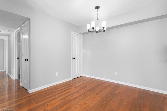 empty room featuring a textured ceiling, a chandelier, and hardwood / wood-style flooring