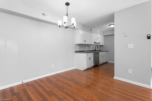 kitchen featuring a textured ceiling, white cabinets, dark wood-type flooring, hanging light fixtures, and stainless steel dishwasher