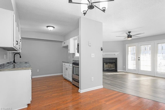 kitchen with a textured ceiling, white cabinets, dark hardwood / wood-style flooring, sink, and electric range