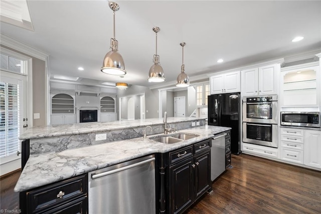 kitchen featuring white cabinetry, sink, decorative light fixtures, and appliances with stainless steel finishes