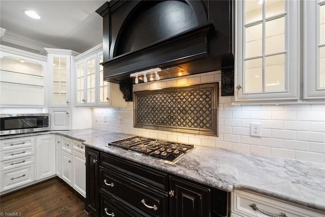 kitchen featuring stainless steel appliances, white cabinetry, custom range hood, and backsplash