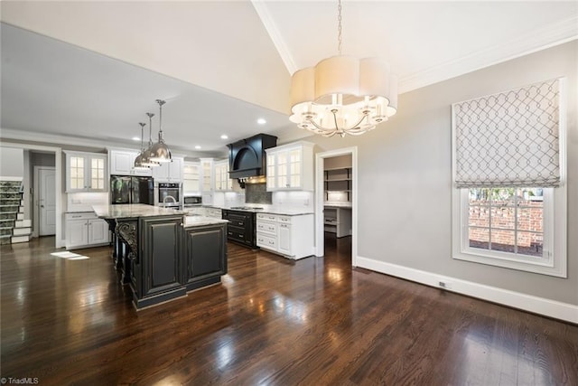 kitchen featuring white cabinetry, hanging light fixtures, a center island with sink, ornamental molding, and stainless steel appliances