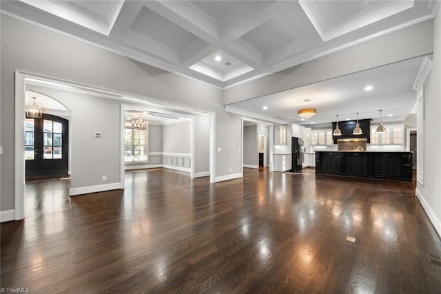 unfurnished living room with ornamental molding, dark hardwood / wood-style floors, an inviting chandelier, and french doors