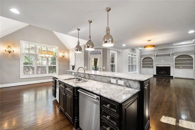 kitchen with pendant lighting, sink, stainless steel dishwasher, light stone countertops, and a center island with sink