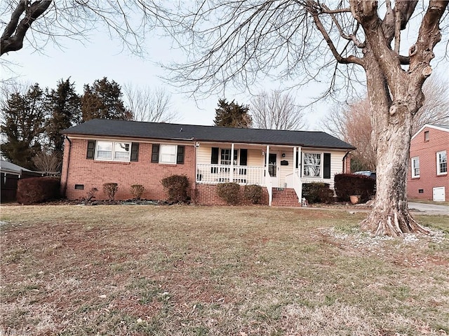 ranch-style house featuring covered porch and a front lawn